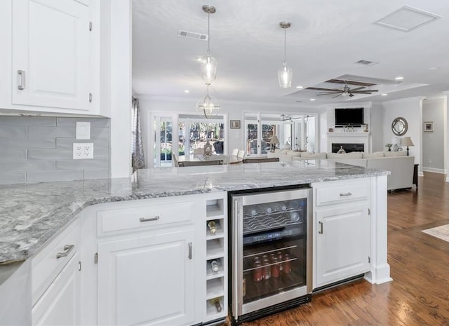 kitchen with beverage cooler, a fireplace, ornamental molding, and dark wood-type flooring