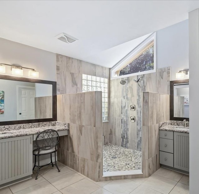 bathroom featuring visible vents, lofted ceiling, walk in shower, vanity, and tile walls