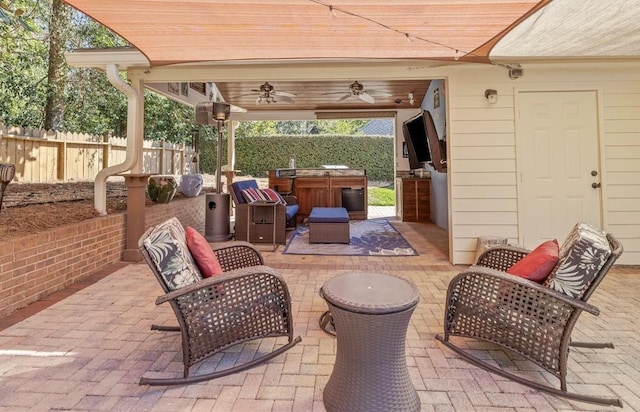 view of patio featuring an outdoor kitchen, fence, and a ceiling fan