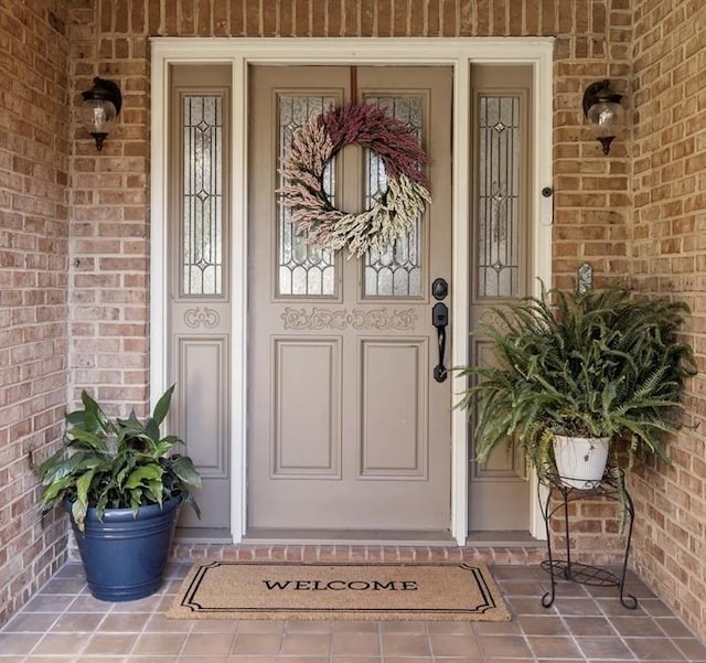 doorway to property featuring covered porch and brick siding