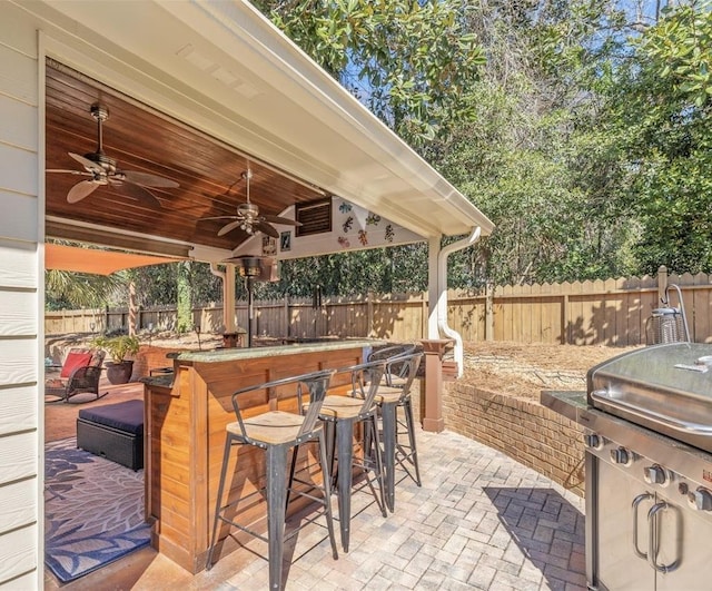 view of patio with outdoor dry bar, fence, grilling area, and ceiling fan