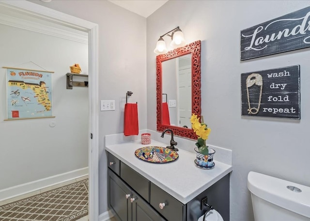 half bath featuring toilet, vanity, and baseboards