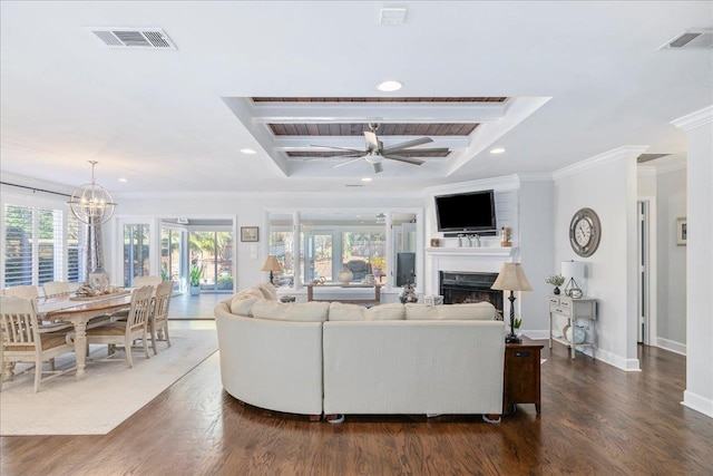 living room featuring dark wood-type flooring, a fireplace, visible vents, and crown molding