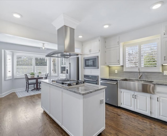 kitchen featuring a sink, a kitchen island, white cabinetry, appliances with stainless steel finishes, and island exhaust hood