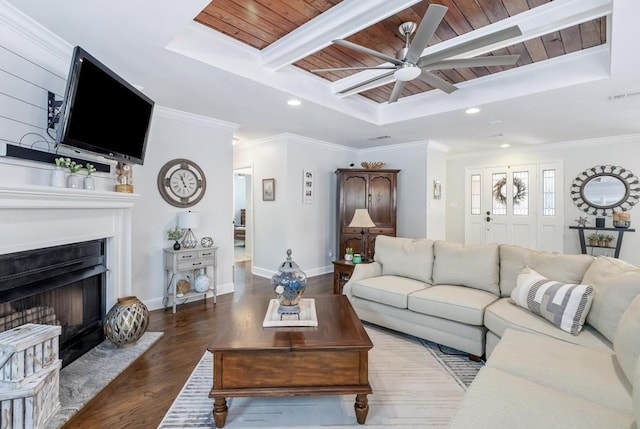 living area featuring baseboards, wood ceiling, wood finished floors, a tray ceiling, and crown molding