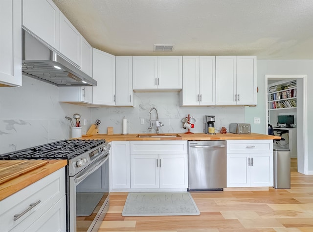 7420 Hickock Ct, Tallahassee, FL 32311 - kitchen featuring appliances with stainless steel finishes, wooden counters, exhaust hood, and light wood-style floors