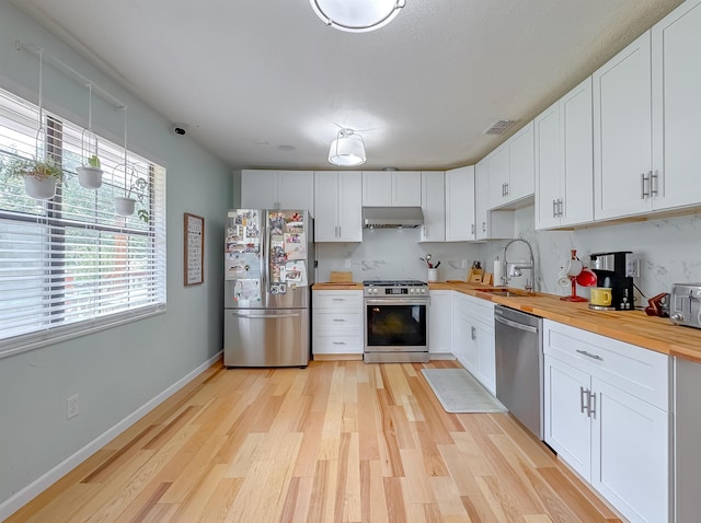 7420 Hickock Ct, Tallahassee, FL 32311 - kitchen featuring stainless steel appliances, wooden counters, exhaust hood, light wood-style floors, and healthy amount of natural light