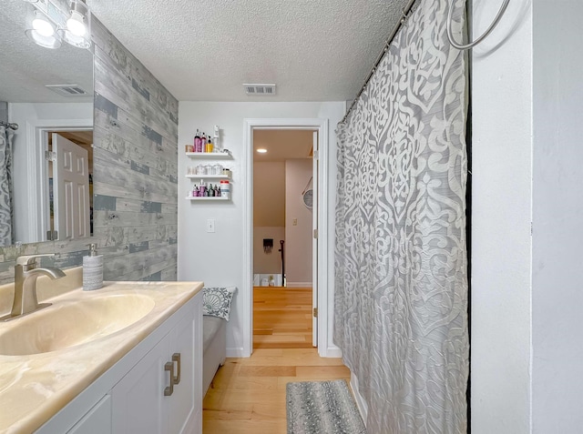 7420 Hickock Ct, Tallahassee, FL 32311 - bathroom featuring wood finished floors, vanity, a textured ceiling, and wood walls