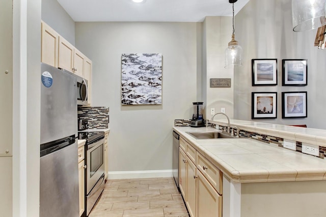 9500 Grand Sandestin Blvd Unit 2103, Walton Beaches, FL 32550 - kitchen featuring appliances with stainless steel finishes, a sink, a peninsula, tasteful backsplash, and tile counters