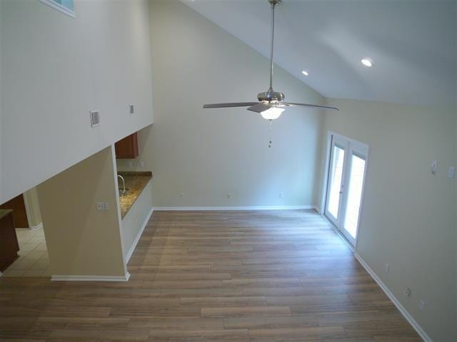 unfurnished living room with light hardwood / wood-style floors, high vaulted ceiling, and ceiling fan