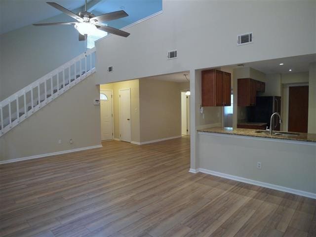 kitchen featuring ceiling fan, sink, high vaulted ceiling, and light wood-type flooring