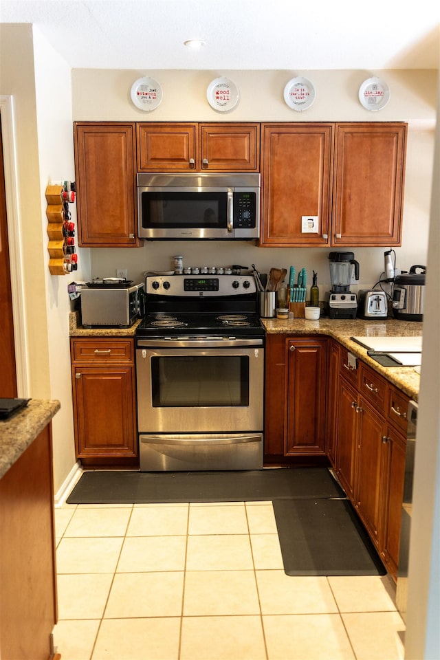 kitchen with light stone counters, light tile patterned floors, and appliances with stainless steel finishes