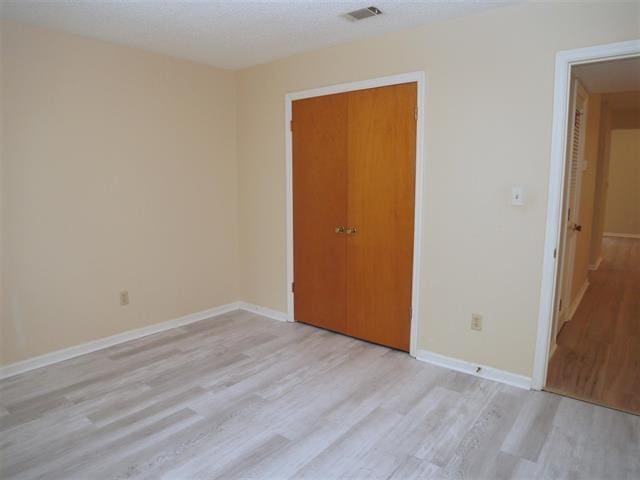 unfurnished bedroom with light hardwood / wood-style floors and a closet