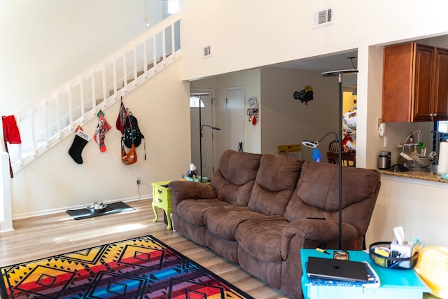 living room with a towering ceiling and light wood-type flooring