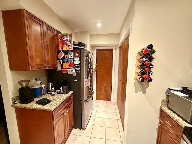 kitchen featuring stainless steel fridge, light stone counters, and light tile patterned flooring