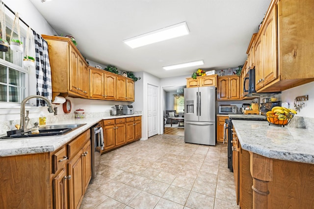 kitchen with light stone countertops, appliances with stainless steel finishes, sink, and light tile patterned flooring