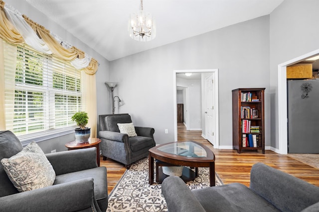 living room with light wood-type flooring, a chandelier, and vaulted ceiling