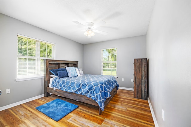 bedroom with multiple windows, wood-type flooring, and ceiling fan