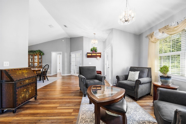 living room featuring lofted ceiling, an inviting chandelier, and hardwood / wood-style flooring