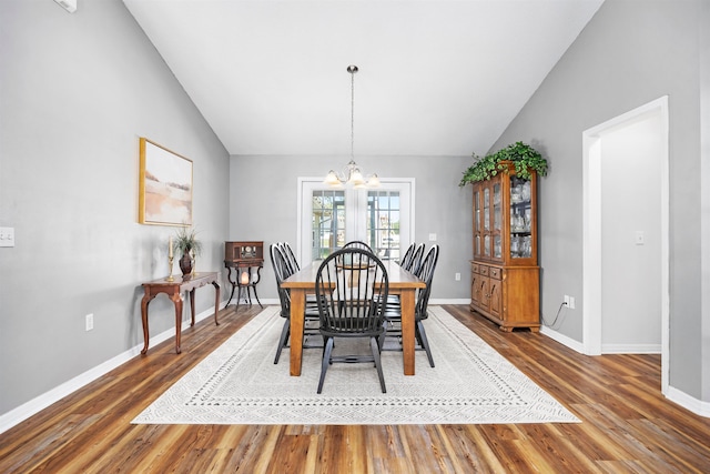 dining space featuring high vaulted ceiling, hardwood / wood-style flooring, and a notable chandelier