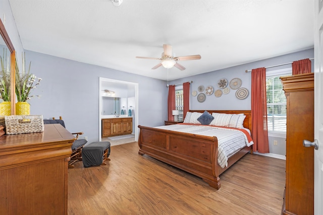 bedroom with connected bathroom, light wood-type flooring, and ceiling fan