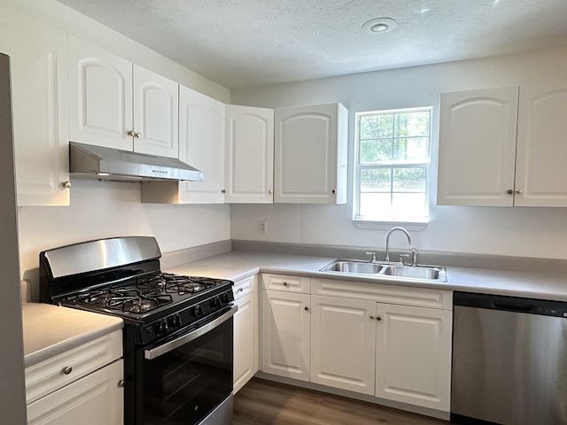 kitchen with white cabinetry, under cabinet range hood, stainless steel dishwasher, a sink, and black range with gas stovetop