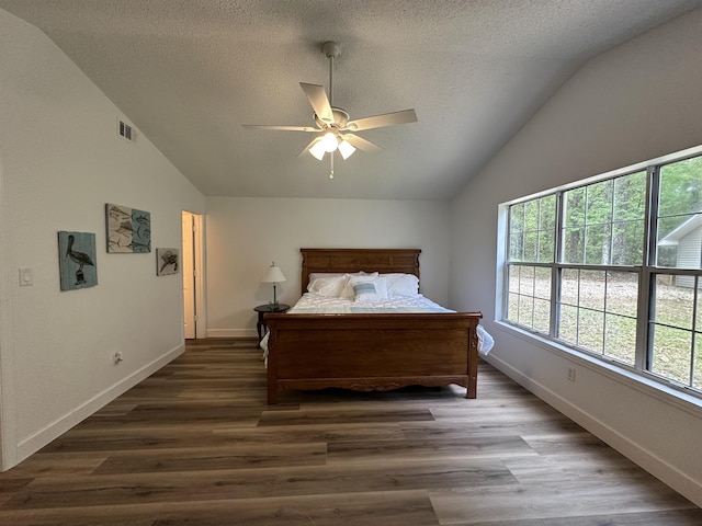 bedroom with wood finished floors, a textured ceiling, vaulted ceiling, and visible vents