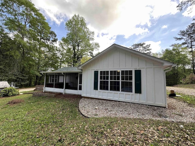 rear view of property featuring a sunroom, board and batten siding, and a yard