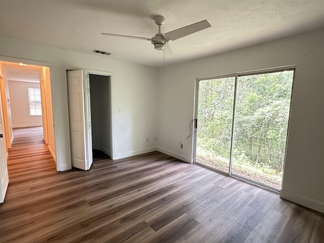 unfurnished bedroom with baseboards, access to exterior, wood finished floors, and a ceiling fan