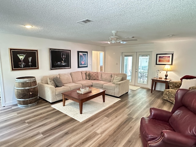living area with visible vents, wood finished floors, french doors, and a textured ceiling
