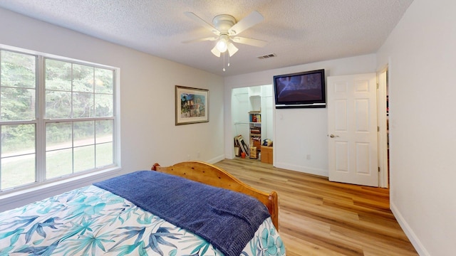 594 Green Oaks Rd, Havana, FL 32333 - bedroom with light wood finished floors, multiple windows, a textured ceiling, and a ceiling fan