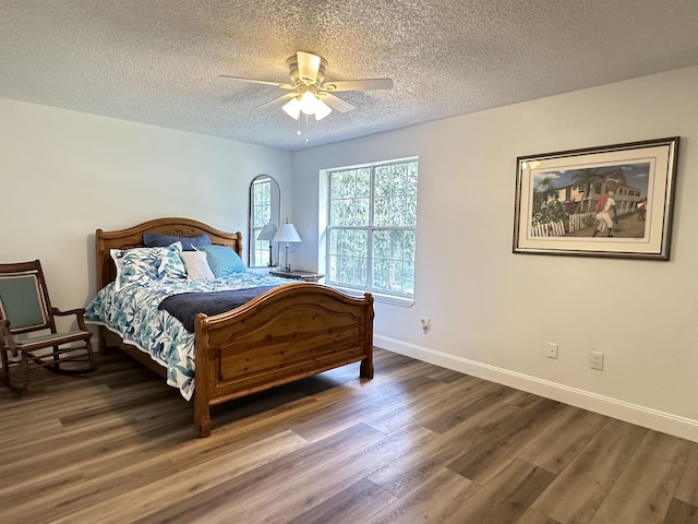 bedroom featuring baseboards, a textured ceiling, wood finished floors, and a ceiling fan