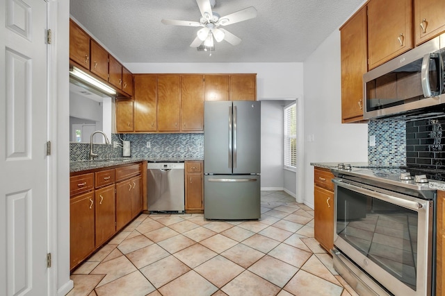 1520 Breamstone Rdg, Tallahassee, FL 32312 - kitchen featuring stainless steel appliances, a sink, brown cabinetry, ceiling fan, and a textured ceiling