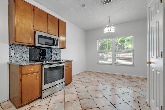1520 Breamstone Rdg, Tallahassee, FL 32312 - kitchen featuring stainless steel appliances, tasteful backsplash, a chandelier, brown cabinetry, and a textured ceiling
