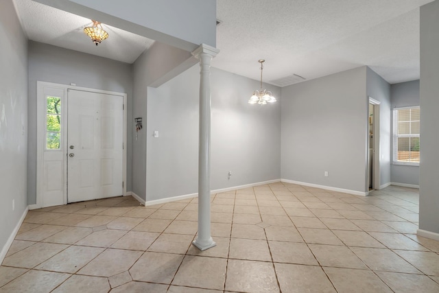 1520 Breamstone Rdg, Tallahassee, FL 32312 - entryway with a chandelier, light tile patterned floors, baseboards, a textured ceiling, and decorative columns