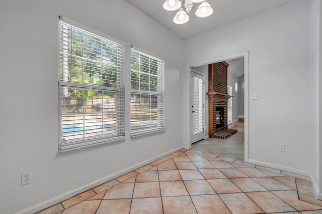 1520 Breamstone Rdg, Tallahassee, FL 32312 - unfurnished dining area with a chandelier, a brick fireplace, light tile patterned floors, and baseboards