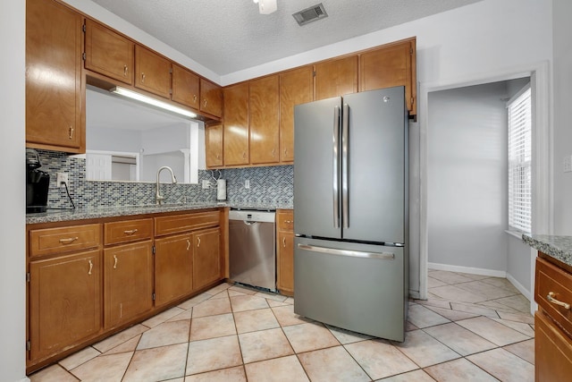 1520 Breamstone Rdg, Tallahassee, FL 32312 - kitchen with stainless steel appliances, a sink, brown cabinets, backsplash, and a textured ceiling