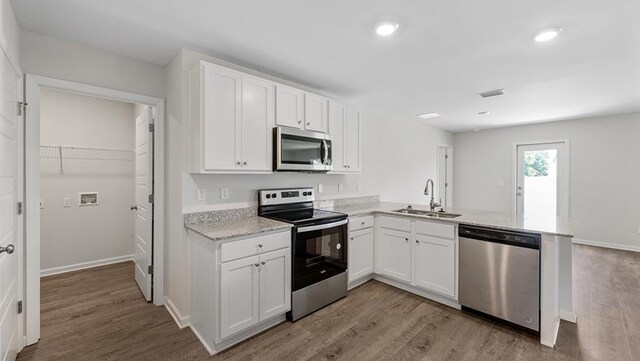 kitchen with white cabinetry, sink, stainless steel appliances, and light hardwood / wood-style floors