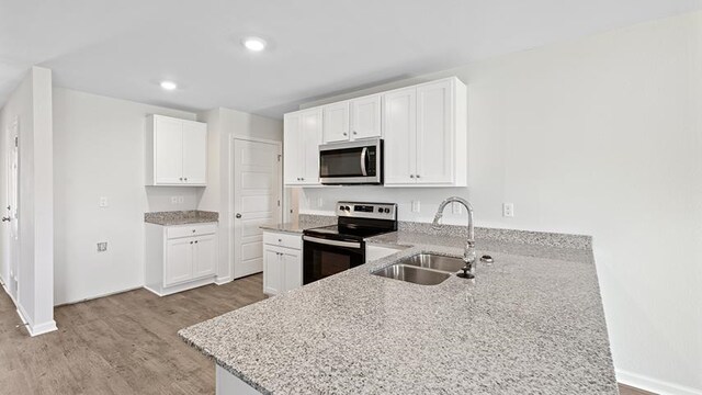 kitchen featuring white cabinets, sink, appliances with stainless steel finishes, light hardwood / wood-style floors, and light stone counters