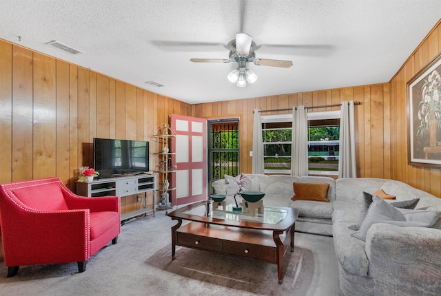 105 Goff St, Perry, FL 32347 - living room featuring wood walls, carpet floors, ceiling fan, and a textured ceiling