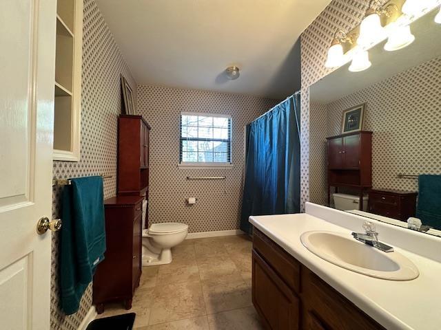 bathroom with an inviting chandelier, tile patterned floors, vanity, and toilet