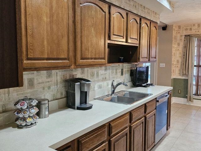 kitchen featuring light tile patterned flooring, stainless steel dishwasher, sink, and decorative backsplash