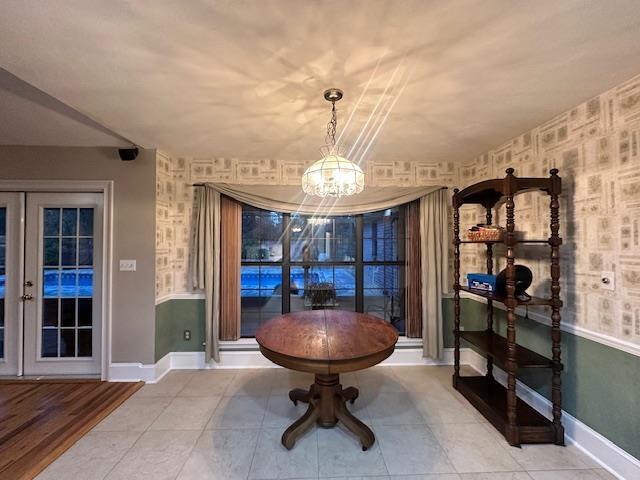 dining space with light tile patterned flooring, a chandelier, and french doors