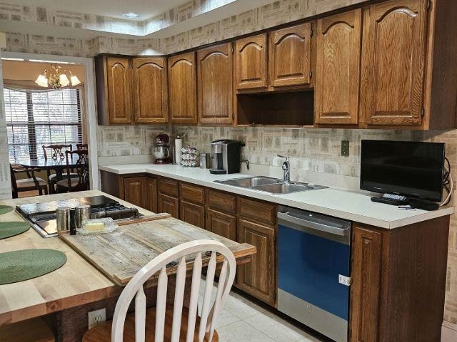 kitchen featuring light tile patterned flooring, sink, an inviting chandelier, appliances with stainless steel finishes, and backsplash