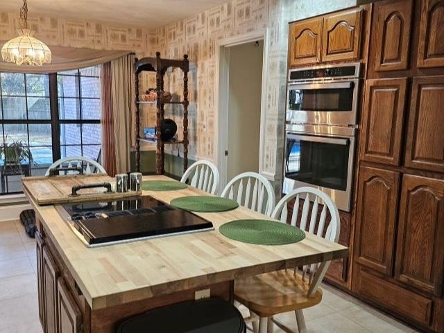 kitchen featuring double oven, a chandelier, hanging light fixtures, a center island, and black electric cooktop