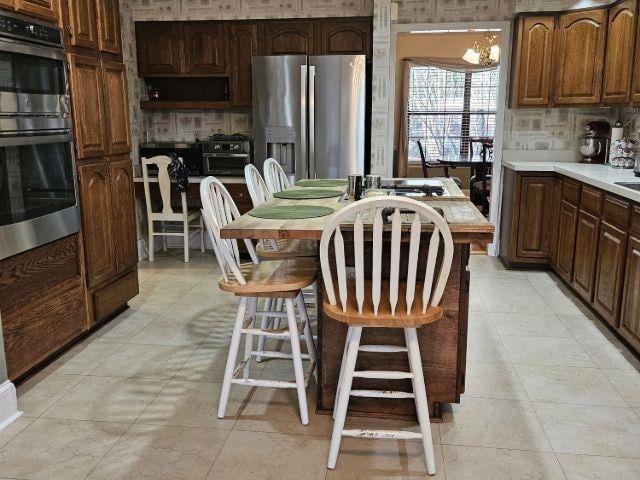 kitchen featuring an inviting chandelier, stainless steel appliances, a center island, a kitchen breakfast bar, and decorative backsplash