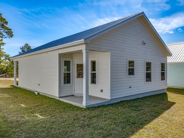 back of house with a patio and a lawn