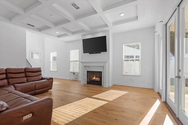 living room featuring coffered ceiling, a fireplace, and light wood-type flooring