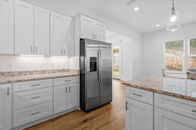 kitchen featuring light hardwood / wood-style flooring, stainless steel fridge, hanging light fixtures, light stone counters, and white cabinets