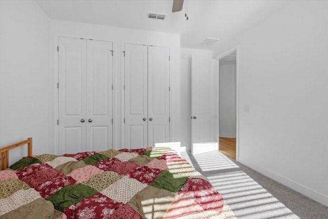 carpeted bedroom featuring multiple closets and ceiling fan